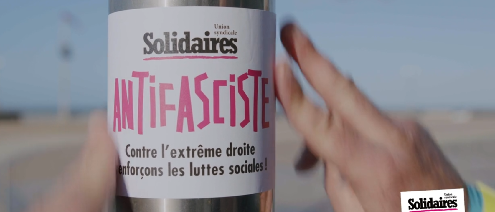 collage d'autocollant antifa solidaires sur un poteau